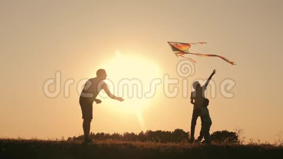 一个幸福的家庭一家人在夏天的夕阳下发射风筝飞向天空视频的预览图