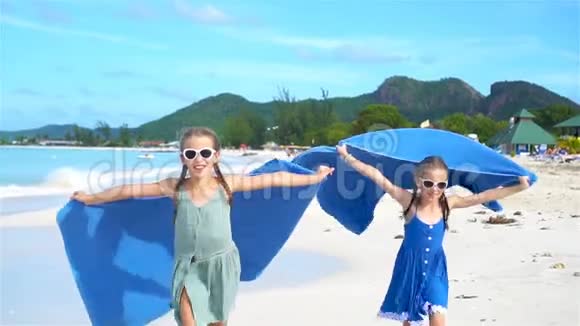 小女孩在热带度假期间用沙滩巾玩乐视频的预览图