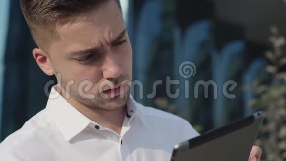 一位年轻商人的肖像他在外面的平板电脑上工作视频的预览图