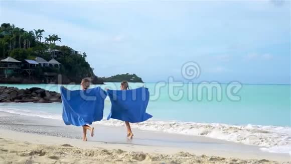 小女孩在热带度假期间用沙滩巾玩乐视频的预览图