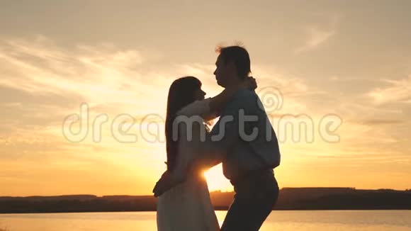 爱的男人和女人在湖底明亮的阳光下跳舞日落时分在海滩上跳舞的情侣快乐视频的预览图
