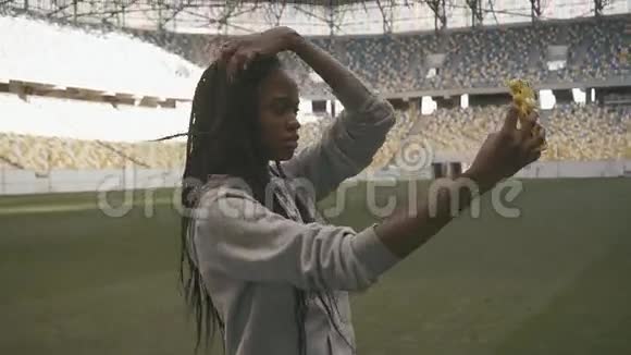 年轻美丽的非裔美国妇女穿过体育场做自拍视频的预览图
