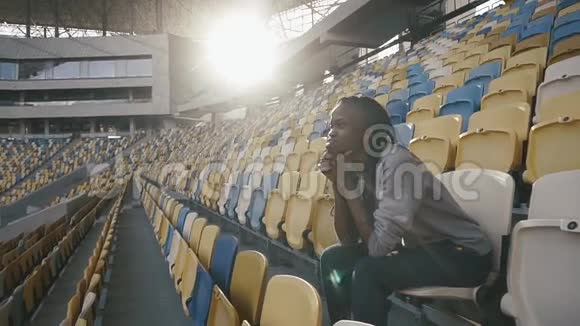 年轻的非裔美国列车员坐在体育场上固定地寻找东西的画像视频的预览图