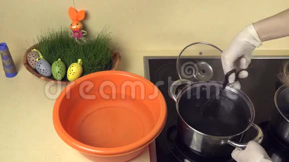 手拿彩蛋从有颜料的锅水到有水的塑料碗视频的预览图