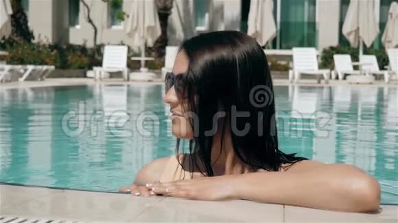 年轻美丽的太阳镜女郎在游泳池享受水视频的预览图
