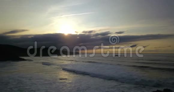 西班牙北部岩石海岸线的空中镜头海滩有海浪日落时有云视频的预览图