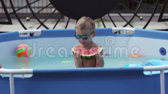 戴黑眼镜的男孩在游泳池里吃西瓜视频的预览图