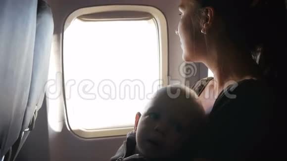 婴儿在飞行过程中坐在母亲的腿上他环顾四周摸着皮带视频的预览图