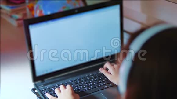 小女孩带着耳机在笔记本电脑上玩网络游戏电脑上的小女孩写了一个信息生活方式视频的预览图