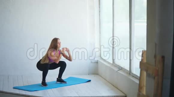 蹲下美丽的年轻女子蹲在健身室视频的预览图