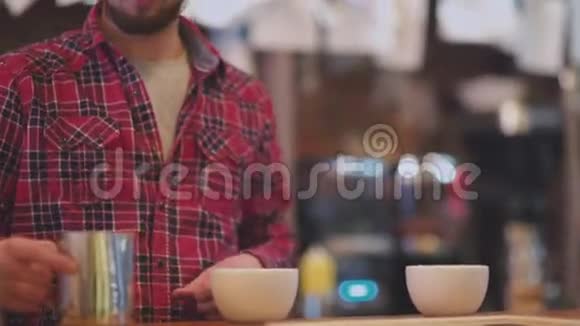 两杯咖啡咖啡杯里倒着泡沫牛奶的咖啡师视频的预览图