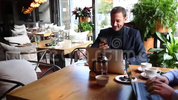 两个商人坐在咖啡桌上用手提电脑喝茶聊天视频的预览图