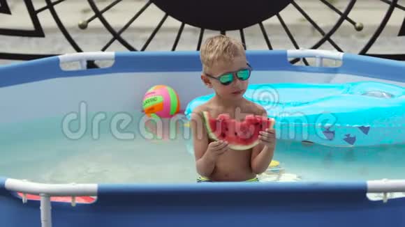 戴黑眼镜的男孩在游泳池里吃西瓜视频的预览图