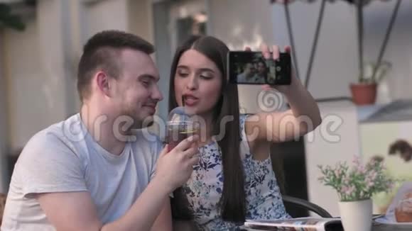 节日快乐的一对情侣坐在咖啡馆外的桌子上自拍视频的预览图