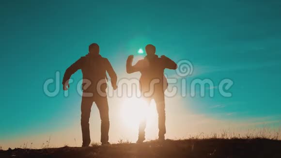 团队合作的人从幸福胜利中跑出来日落时分两名徒步旅行者带着背包去徒步旅行视频的预览图