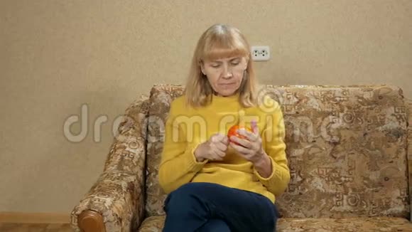 女性年龄在家里在沙发上吃水果她削掉一块柿子享受着味道健康观念视频的预览图