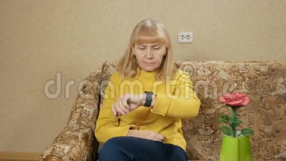 女人的年龄是在家里沙发上的智能手表上留言她仔细阅读了重要的信息视频的预览图