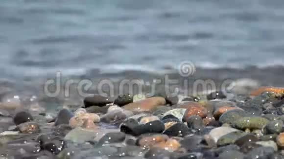 海浪拍打倒了一大片多色卵石特写镜头视频的预览图