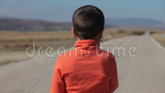男孩看着通往山上的路吃棒棒糖视频的预览图