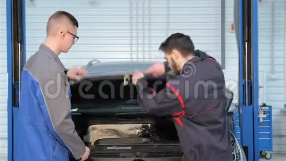 两个机械师在汽车服务中心打开车盖视频的预览图