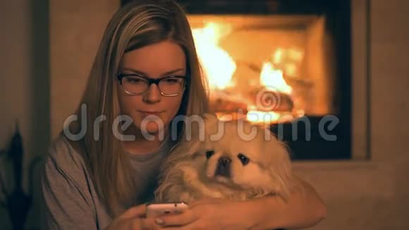 带狗的女孩在壁炉旁用电话视频的预览图