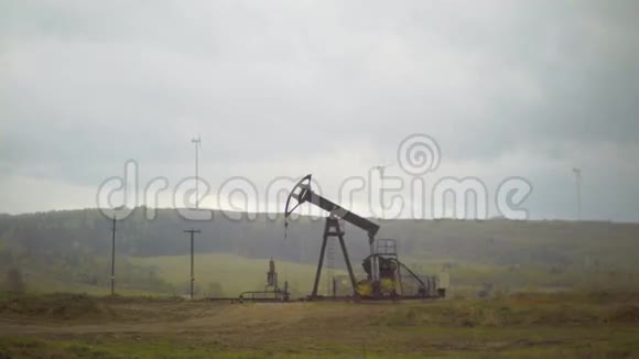 油井千斤顶泵和一个风力发电场的背景为春季视频的预览图