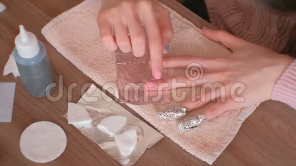 去除指甲中的凝胶抛光女人倒掉棉垫上的液体把它放在钉子上把箔包起来关闭视频的预览图