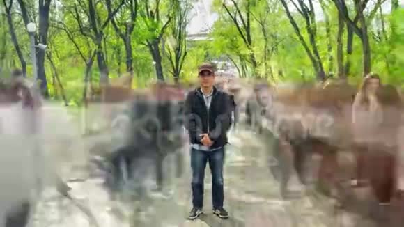 男人独自站在模糊的人群中在背景绿树上摄像机快到了时间流逝视频的预览图