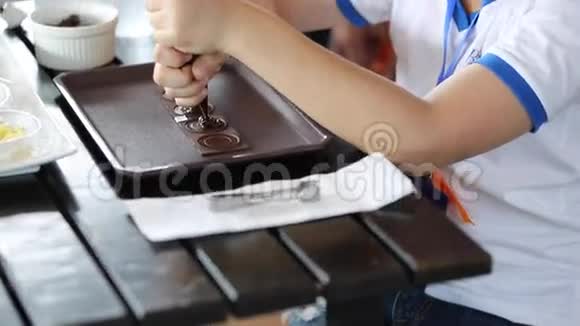 小亚洲男孩用手做糖果用手捏融化的巧克力做蛋糕的零件视频的预览图