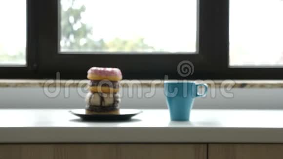 靠近窗户的盘子里放着一杯咖啡和甜甜圈视频的预览图