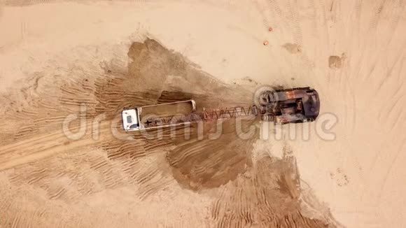 正上方的挖掘机将沙子倒入卡车在施工现场视频的预览图