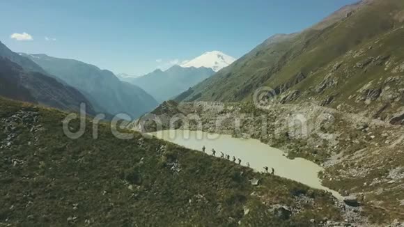 徒步旅行的人走在山间小路上可以看到湖和雪峰视频的预览图