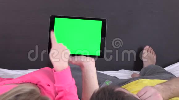 一对情侣在床上看着白色平板电脑上的东西绿色的屏幕视频的预览图