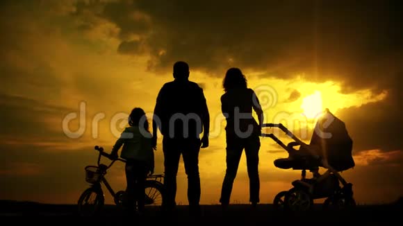 日落时分快乐的父母和他们的孩子在户外玩得很开心剪影视频的预览图