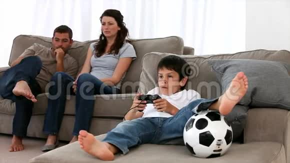 可爱的小男孩玩电子游戏父母喜欢看视频的预览图