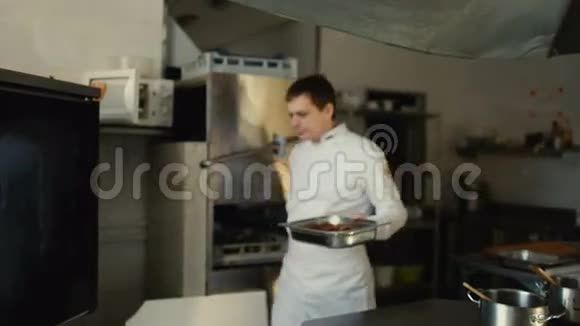 专业厨师把肉菜放到餐厅厨房的烤箱里视频的预览图