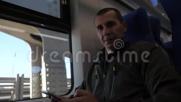 乘坐地铁列车的中年智能手机坐在窗口旁的一位不知名的旅行者向社交媒体发送短信视频的预览图