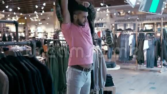 在购物中心试夹克的男性顾客视频的预览图