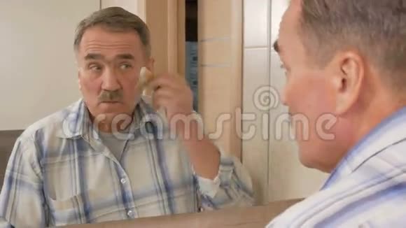 在浴室刮胡子的老人它使用剃须泡沫和一次性剃须刀自理的概念视频的预览图