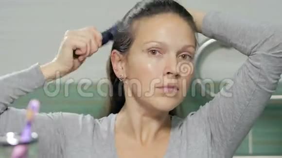 一个年轻迷人的女人梳头在浴室里梳着辫子她把一根长长的头发视频的预览图