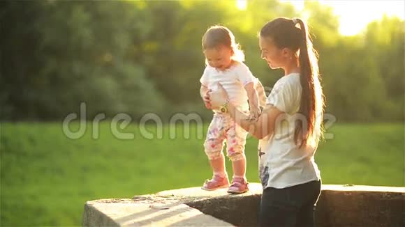 妈妈和女儿在大自然中散步美丽的妈妈和她的小朋友牵着手在公园里温暖地散步视频的预览图