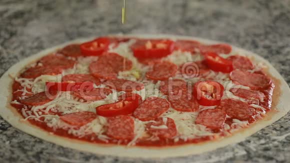 在商业厨房的披萨上添加橄榄油的厨师视频的预览图