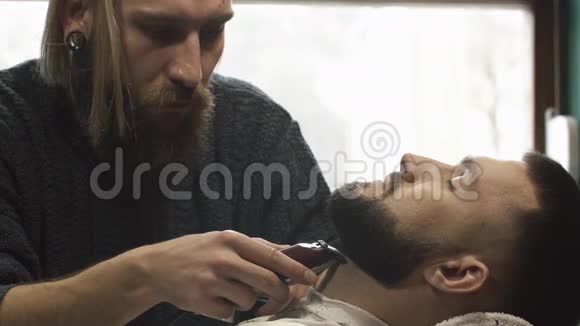 理发店理发师用剪子剪胡子理发师和电动修剪机一起工作视频的预览图