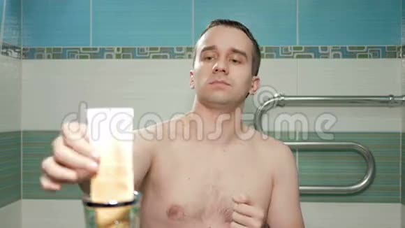 年轻有魅力的男人在酒店房间的浴室里涂满了奶油手他倒了奶油搓了搓手他是视频的预览图