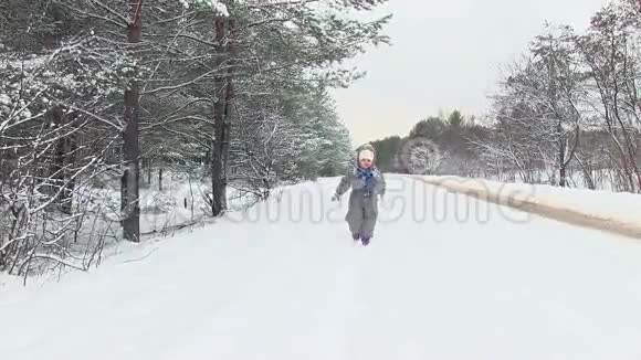 冬天森林里的小孩子穿过雪朝镜头跑去视频的预览图