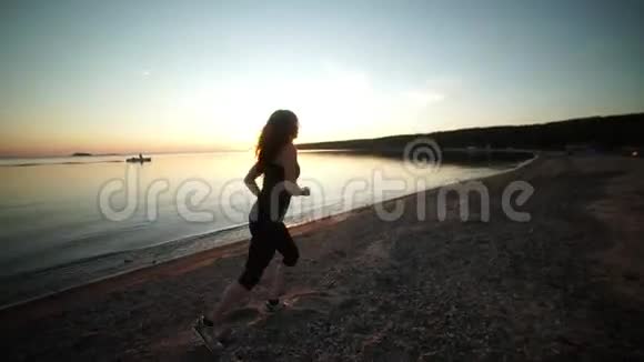 在日落时分运动的女性在海边的长廊上奔跑视频的预览图
