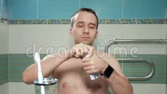 年轻迷人的男人在浴室刷牙他在刷子上涂抹牙膏并仔细清洁视频的预览图