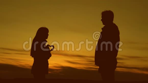 男人和女人在夕阳下抱着爱的心视频的预览图
