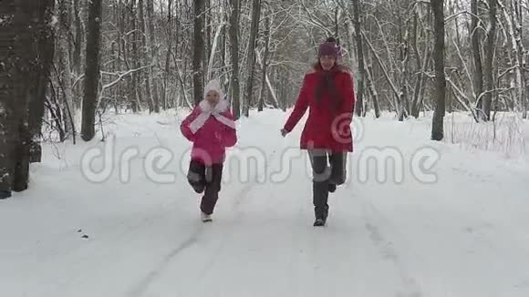 母亲带着孩子在冬天在公园里跑步慢动作视频的预览图