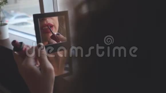 年轻女子看着镜子里的自己画着嘴唇视频的预览图